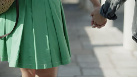 Closeup-of-young-couple-walking-with-intertwined-fingers.